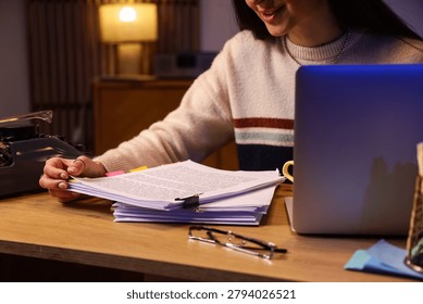 Female screenwriter with script on table in office at night