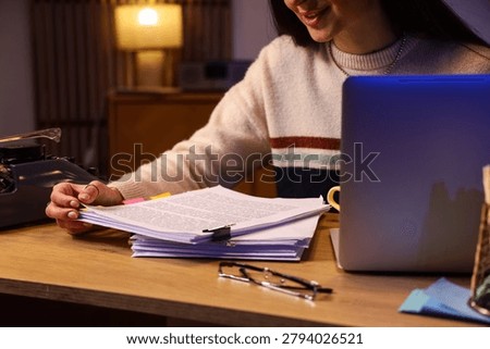 Female screenwriter with script on table in office at night
