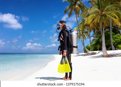 Female scuba diver in full equipment stands on a tropical beach ready to enter the water - Powered by Shutterstock