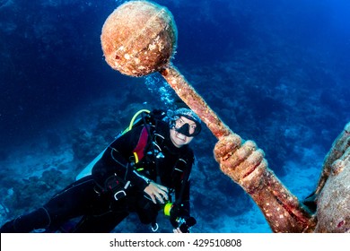 Female SCUBA Diver and a Large Underwater Statue - Powered by Shutterstock