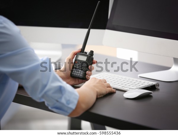Female security guard holding portable radio in\
hand at workplace