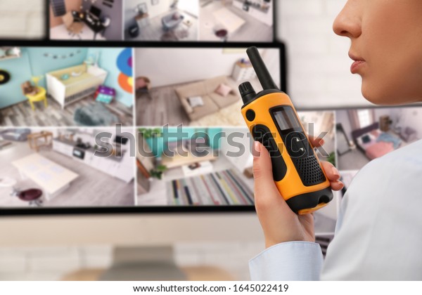 Female security guard with portable\
transmitter near monitors at workplace,\
closeup