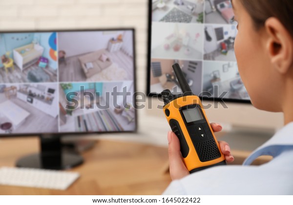 Female security guard with portable\
transmitter near monitors at workplace,\
closeup