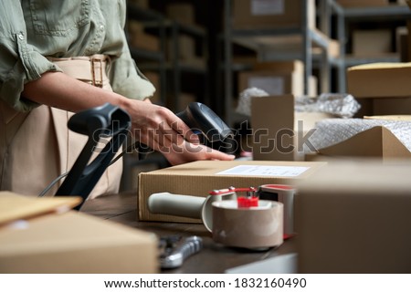 Female seller online store worker holding scanner scanning parcel bar code packing e commerce post shipping box preparing online retail shop order in dropshipping delivery service warehouse.