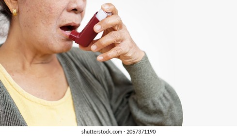 Female Senior Patient Uses Brown Asthma Inhaler For Relief Asthma. Concept : Health Care At Home.  Pharmaceutical Products For Treatment Symptoms Of Asthma Or COPD. Use Under Prescription. 