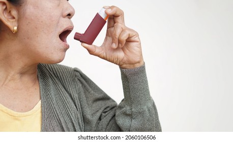 Female Senior Patient Uses Brown Asthma Inhaler For Relief Asthma. Concept : Health Care At Home.  Pharmaceutical Products For Treatment Symptoms Of Asthma Or COPD. Use Under Prescription Of Doctor.