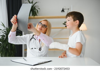 Female senior pediatrician showing x-ray of wrist and hand to little boy patient. Child at doctors office. - Powered by Shutterstock