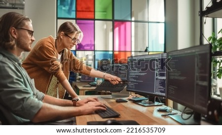Female Senior Software Engineer Gives Advice to Male Junior Developer, Pointing at Desktop Computer Display With Code. Caucasian Woman Offers New Features, Helps Fixing Bugs in Modern SaaS Platform.
