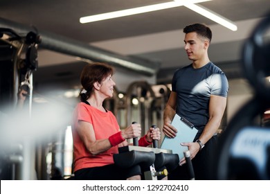 A female senior with a young trainer doing strength workout exercise in gym. - Powered by Shutterstock