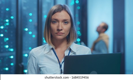 Female Server Technician Doing Checkup Operations On Laptop Computer Coworking In Cyber Server Room. Portrait Of Professional Woman Engineer In Data Center Interior.