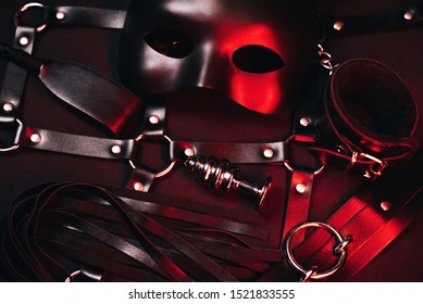 Female Set Of Sex Toys From A Sex Shop For BDSM Sex With Submission And Domination. Mask, Leather Belt, Choker, Handcuffs, Whip And Anal Plug