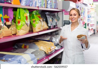 Female Shop Assistant Offering Food For Pets In Pet Store