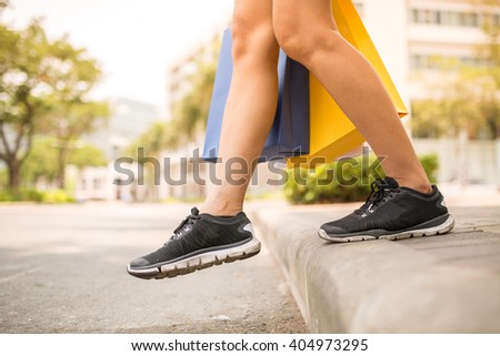 Female shopaholic in sport shoes crossing road