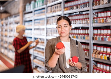 Female shopper choosing pottery glaze jars in a pottery specialty store - Powered by Shutterstock