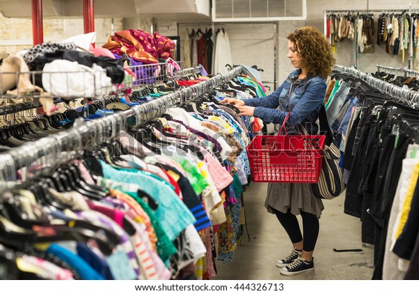 Female\
Shopper In Thrift Store browsing through\
clothing
