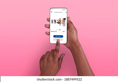Female Shopping Concept. Above top overhead view of black woman browsing online make up store on her smart phone, isolated on pink background, touching screen. Customer ordering via internet