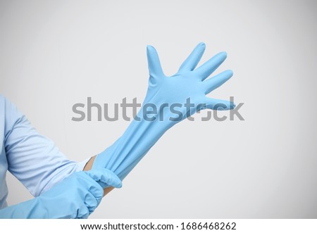 Female shoulder putting on sterile gloves. Hand woman wearing gloves on grey background. Healthcare and Medical concept.