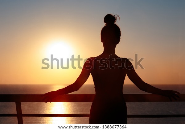 Female\
Silhouette at the Balcony Admiring Sunrise. Woman looking forward\
into the horizon hoping for future accomplishes\
