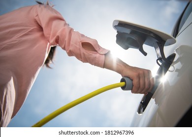 Female Silhouette Charging A Electric Car, Photo From Below