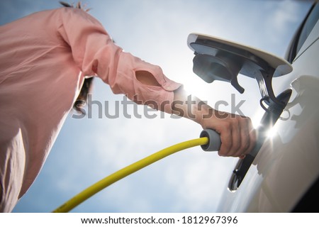 Female silhouette charging a electric car, photo from below