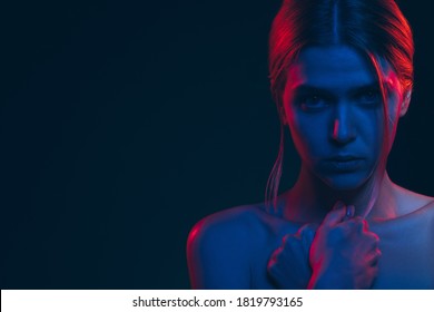 Female silhouette portrait. Feeling helpless. Worried woman bare shoulder in neon light glow. Looking at camera isolated on black copy space. Abuse violence. Toxic relationship. Feminine power