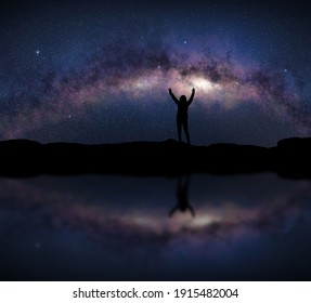 Female silhouette raises arms in front of a bright Milky Way night sky. Concept about open air sport activity, adventure, travel. - Powered by Shutterstock