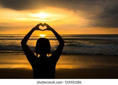 Female Silhouettes Hands Making A Heart Shape With Sunset