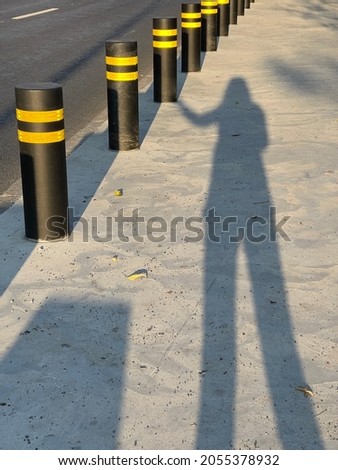 Female silhoutee touching black fencing bollard with yellow reflective stripes