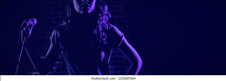 Female singer looking away while standing at nightclub