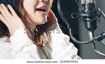 Female singer recording in studio.