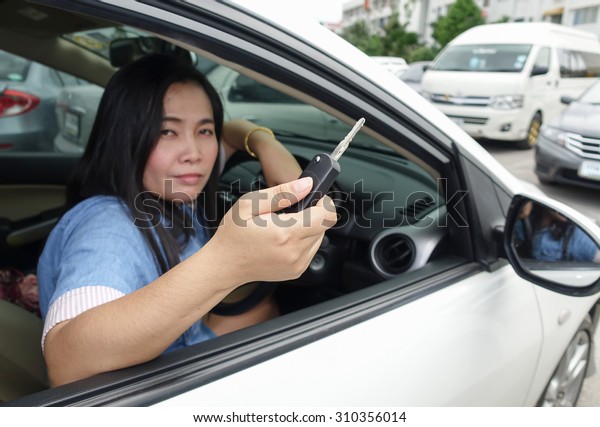 Female\
sitting in car showing key at the car\
parking
