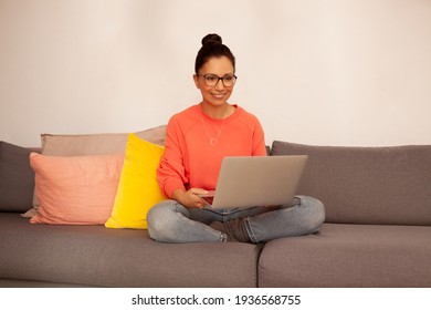 female sitting on sofa using technology ad relaxing at home