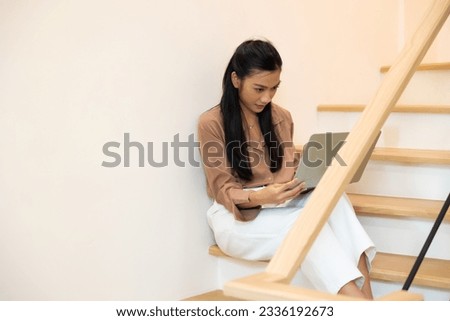 Female sitting on stairs. Asian business working woman work online job on laptop computer at smallbusiness home office. Work from home