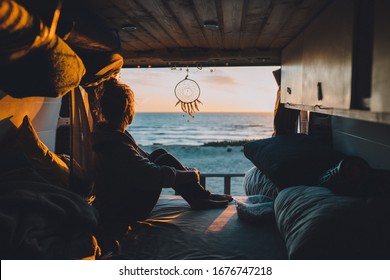 A female sitting in the van and admiring the sunset in the beach