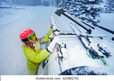 Female Skier Fastening Skis To Car Roof's Rails