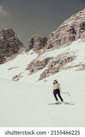 Female Skier On Downhill Slope Surrounded With Spectacular Mountain Ridge.