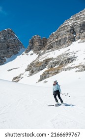Female Skier On Downhill Slope Surrounded With Spectacular Mountain Ridge.
