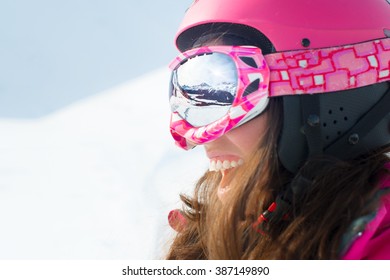 Female Skier With Skis Smiling And Wearing Ski Glasses. With Reflection Panorama Of Mountains