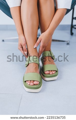 Female slender legs in green summer sandals. Women's leather shoes