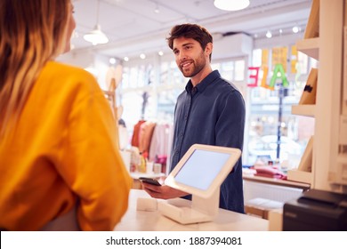 Female Small Business Owner Accepting Contactless Payment In Shop From Customer Using Mobile Phone