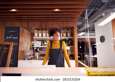 Female Small Business Owner Of Coffee Shop In Mask Standing Behind Counter During Health Pandemic