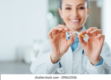 Female smiling doctor breaking a cigarette, stop smoking and prevention concept