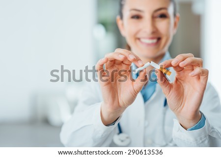 Female smiling doctor breaking a cigarette, stop smoking and prevention concept