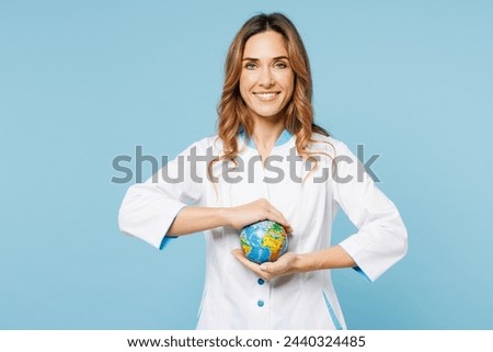 Female smiling happy doctor woman she wears white medical gown suit work in hospital clinic office hold in palms Earth map globe isolated on plain blue background studio. Health care medicine concept