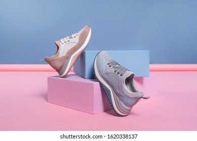 Female Sneakers Of Different Colors, But Of The Same Model, Stand On A Pink, Blue Stand From The Studio. Promotional Photo