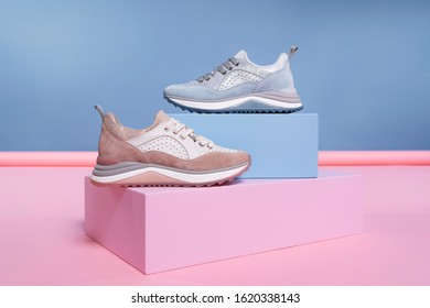 Female Sneakers Of Different Colors, But Of The Same Model, Stand On A Pink, Blue Stand From The Studio. Promotional Photo