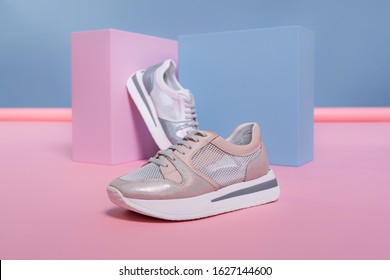 Female Sneakers Of Different Colors, But Of The Same Model, Stand On A Pink, Blue Stand From The Studio. Promotional Photo