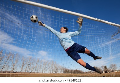 A Female Soccer Player Diving To Catch The Ball