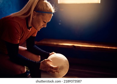 Female soccer player holding a ball and concentrating before the match while sitting in dressing room. - Powered by Shutterstock