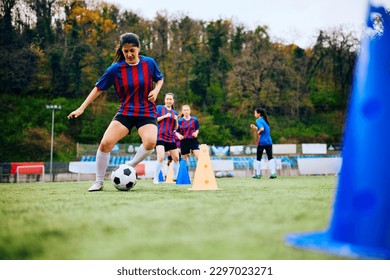 Female soccer player leading the ball among cones during sports training.  Copy space. - Powered by Shutterstock